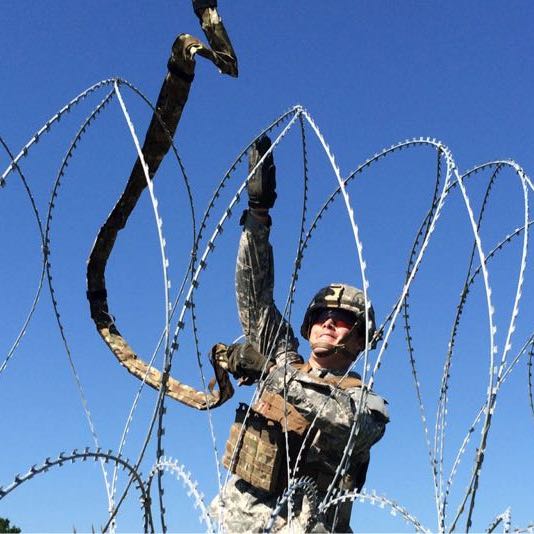 Soldier throwing an Bandolier across barbed wire